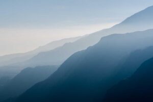 Blue mountains overlap in layers under a hazy sky, peaceful and untouched—nature’s own form of pest control in the distance.