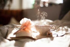 A steaming cup of tea sits on an open notebook with a pink pen—perfect for planning your next pest control project in the sunlit bed.